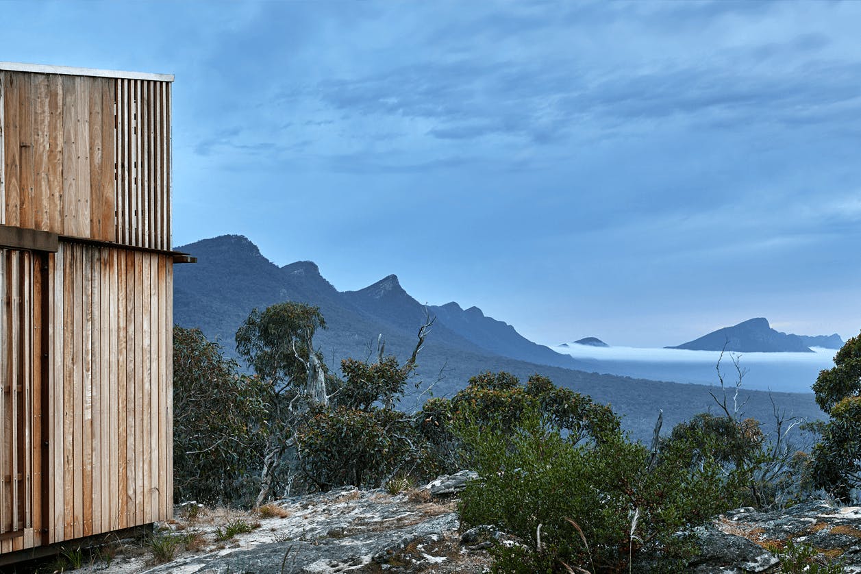 A cabin on a hill overlooking a wide mountain range.